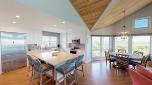 A modern kitchen with a central island, stainless steel appliances, and a dining area with a view. - Fabulous oceanfront home with private beach access (Isle of Palms)
