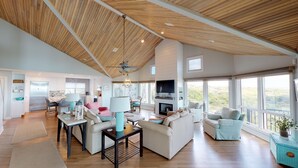 A spacious living area with a high ceiling, a fireplace, and large windows offering a view of the outdoors. - Fabulous oceanfront home with private beach access (Isle of Palms)