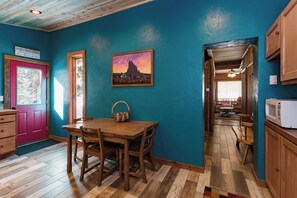 Una cocina acogedora con una mesa y sillas de madera, un cuadro en la pared y vistas al comedor.