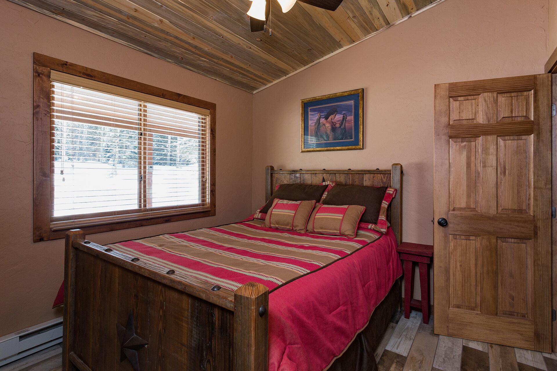 Un letto di legno con una coperta a righe, una testata in legno e una finestra con persiane.