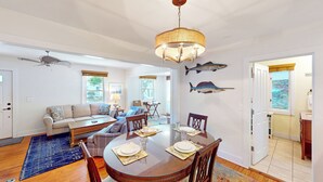 A dining area with a round table set for four, a sofa, and a ceiling fan.
