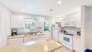A modern kitchen with white cabinets, a granite countertop, a built-in microwave, a stove, and a sink.