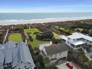 A coastal residential area with a large lawn, a golf course, and a beach.