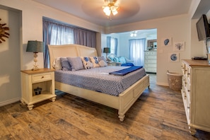 A bedroom with a bed, nightstands, a dresser, and a television.