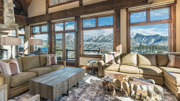 A spacious living room with large windows offering mountain views, a rustic wooden coffee table, and a cozy seating area.