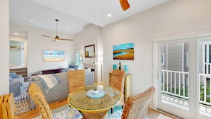 A spacious living room with a glass-top table, wicker chairs, a sofa, and a fireplace. - Villa in Wild Dunes with golf and Lagoon views; close to pool (Isle of Palms)