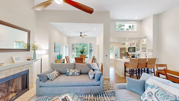 A modern living room with a fireplace, a sofa, and a dining area with chairs. - Villa in Wild Dunes with golf and Lagoon views; close to pool (Isle of Palms)
