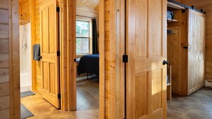 L’intérieur d’une cabane en bois, avec une salle de bain visible, un lit et un grand placard.