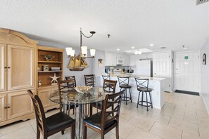A spacious kitchen with a central island, wooden cabinets, and a dining area with a glass table and chairs.