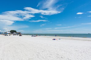 Ein Strand mit weißem Sand, blauem Himmel und ruhiger See.