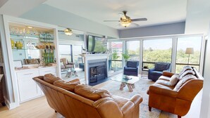 A spacious living area with leather sofas, a fireplace, a television, and a balcony with a view. - Stunning oceanfront condo located in Wild Dunes with ocean and golf views (Isle of Palms)
