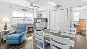 A modern kitchen with white cabinets, a microwave, and a view of the ocean. - Direct Beach Front Views - Surf Song #222 (Madeira Beach)