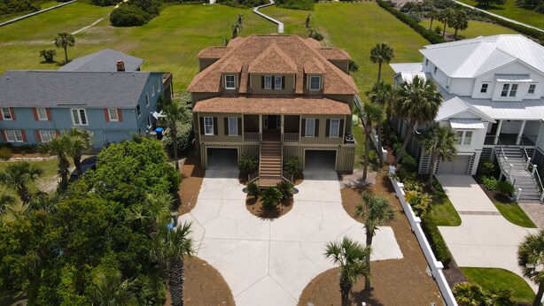 Une grande maison avec un vaste jardin à l’avant, une allée et une vue sur la plage.