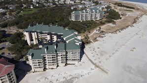 Ett hotell vid stranden med flera balkonger, en sandstrand och en golfbana i bakgrunden.