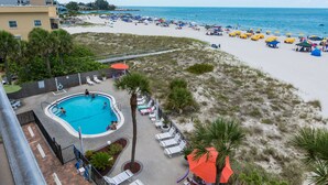 A beach resort with a swimming pool, lounge chairs, and beach umbrellas. - Prime Beachfront Balcony - Madeira Norte #311 (Madeira Beach)
