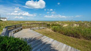 A wooden boardwalk leading to a beach with a clear sky and dunes in the background. - Shipwatch A204: Oceanfront condo, stunning views & private balcony retreat (Isle of Palms)