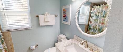 A bathroom with a toilet, sink, and mirror.