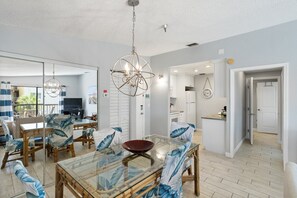 Relax in this stylish living space with a central dining area, kitchen, and hallway leading to additional space.