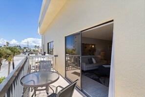 Relax on the balcony with a sofa, chairs, and a rug, offering a tranquil view of the surrounding palm trees.