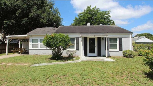 A single-story house with a front porch, a small front yard, and a covered patio area. - Pet friendly with fenced yard, no stairs, walk to beach access, sleeps 6! (Isle of Palms)