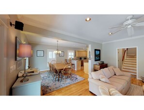 A spacious living area with a dining table, a sofa, and a kitchen in the background.