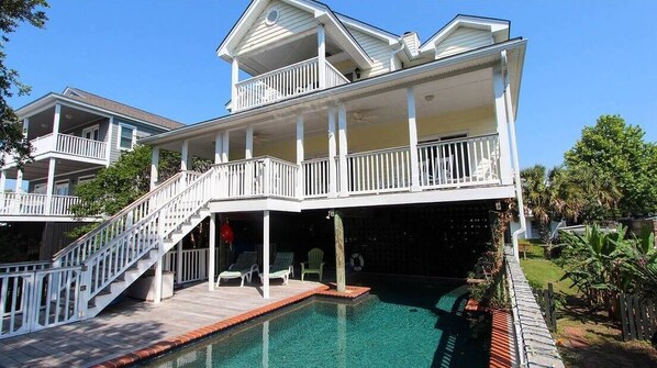 A two-story house with a swimming pool, a covered deck, and a staircase leading to the upper level.