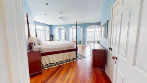 A bedroom with a large bed, wooden headboard, a nightstand, a dresser, and a ceiling fan. - Three story home with sweeping ocean views and game room in Wild Dunes (Isle of Palms)