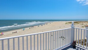 A beach view from a balcony with a railing, ocean, and beachgoers. - Three story home with sweeping ocean views and game room in Wild Dunes (Isle of Palms)