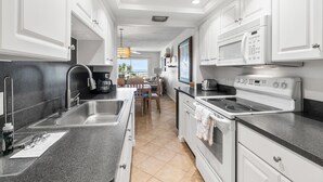 A modern kitchen with white cabinets, a stainless steel sink, a built-in microwave, and an oven.