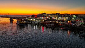 A waterfront hotel with a pier, reflecting the sunset.