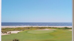 Campo de golf con playa arenosa y vista al océano.