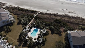 Eine Vogelperspektive eines Resorts mit einem Swimmingpool, umgeben von Palmen und einem Strand.