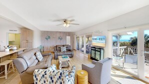 A spacious living area with a large sofa, a coffee table, and a television displaying 'ISLAND REALTY'.