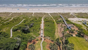 An aerial view of a coastal area with a beach, a boardwalk, and a small building with a gazebo.