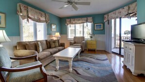 A living room with a sofa, armchair, coffee table, and a television on a cabinet. - Ocean View condo in Wild Dunes (Isle of Palms)