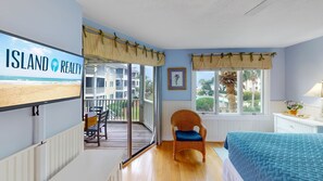 Une chambre avec un balcon, un lit, une chaise et une vue sur la plage.