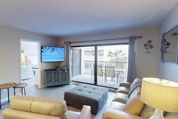 A living room with a sofa, ottoman, and a television on a cabinet.