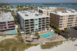 A multi-story hotel with a rooftop pool and a beachfront view.