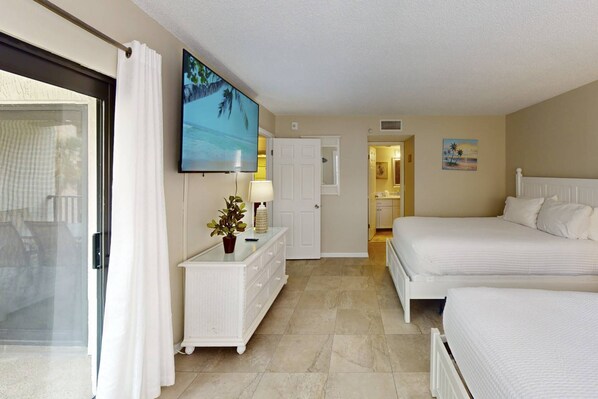 Habitación de hotel con una cama, cómoda, televisión y baño visible a través de una puerta abierta.