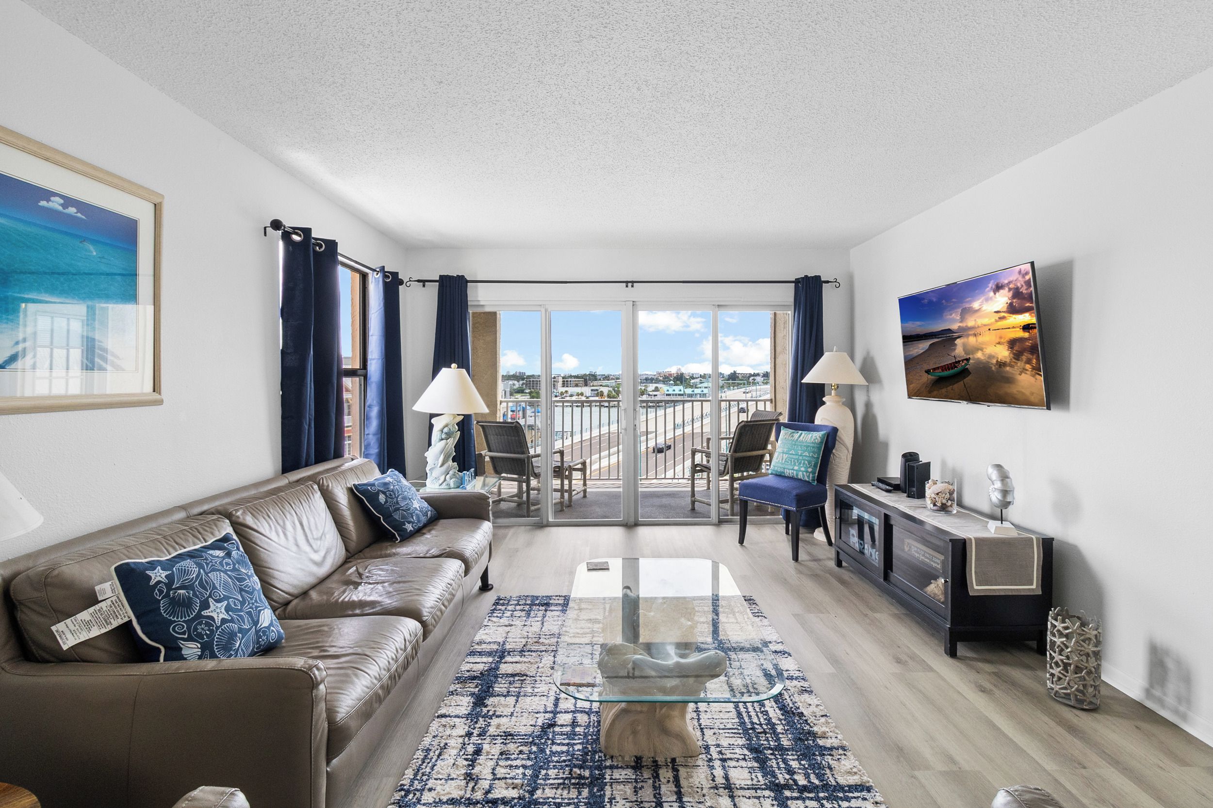 A modern living room with a leather sofa, a glass coffee table, and a view of the city through large windows.