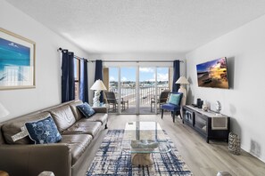 Una sala de estar moderna con un sofá de cuero, una mesa de centro de vidrio y vistas de la ciudad a través de amplios ventanales.