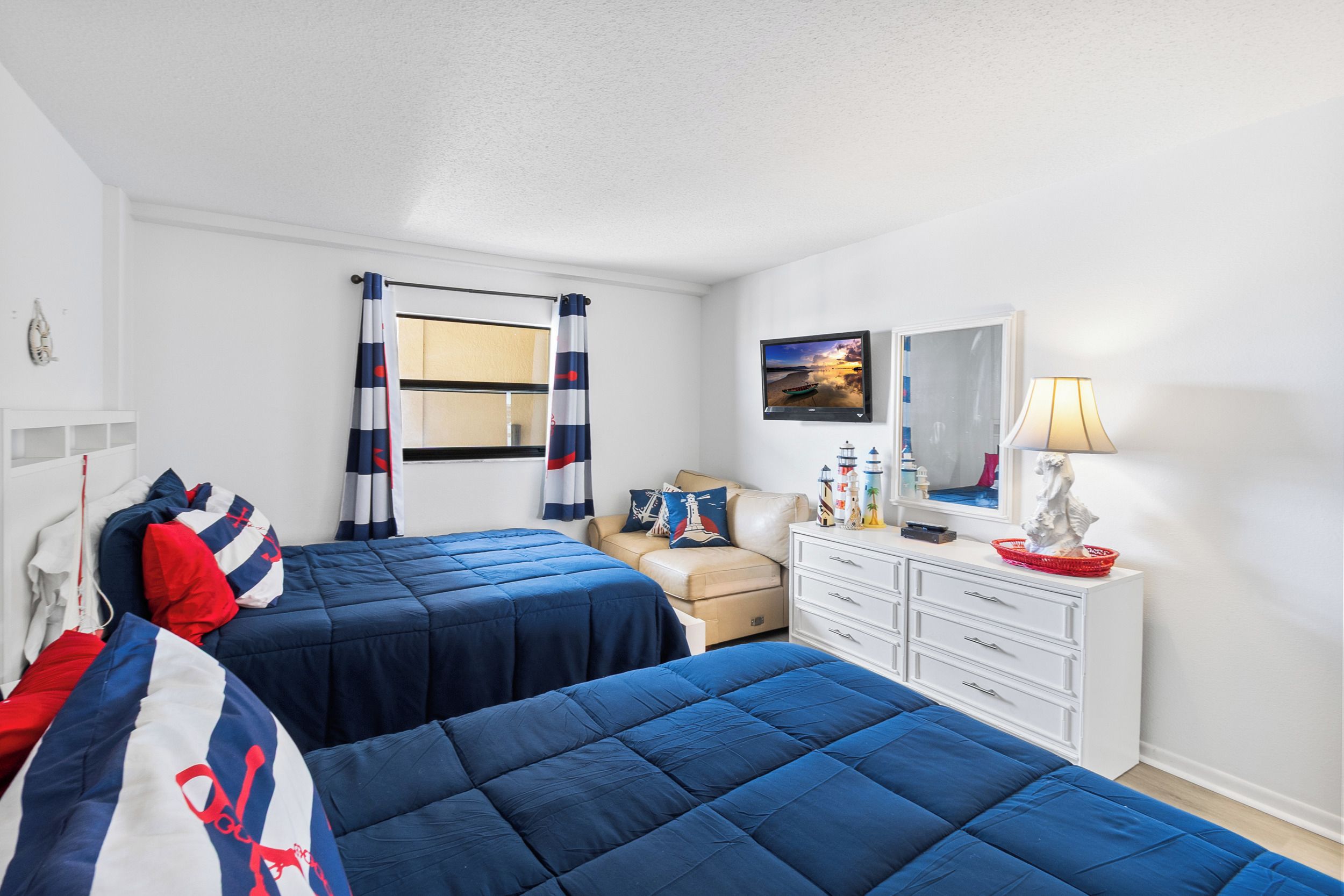 Une chambre avec deux lits, une commode, un miroir et un téléviseur.