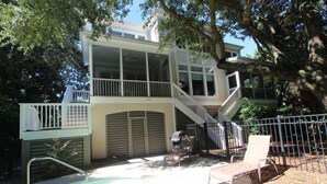 A two-story house with a balcony, a covered patio, and a swimming pool. - Beautifully decorated and spacious home in Wild Dunes with a private pool (Isle of Palms)