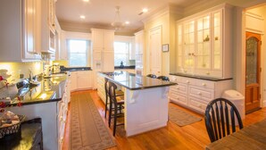 A spacious kitchen with white cabinetry, a central island, and a dining area with a wooden table and chairs. - Beautifully decorated and spacious home in Wild Dunes with a private pool (Isle of Palms)