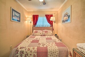 Una camera da letto con un letto, tende rosse, lampade a parete e quadri appesi.