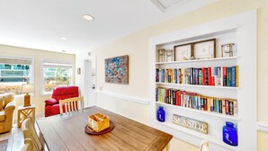 Un coin repas avec une table en bois, des chaises et une bibliothèque remplie de livres.