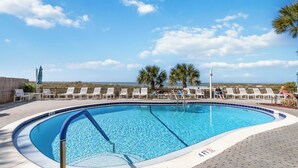 Una piscina con sillones de descanso y vistas a la playa.