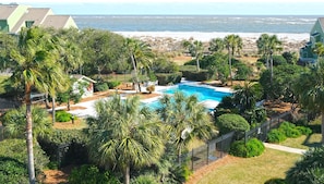 A pool surrounded by palm trees and a view of the ocean.