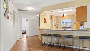 Una cucina con angolo bar, pavimento piastrellato e lampade a sospensione.