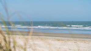 A beach with waves, a clear sky, and a distant person.
